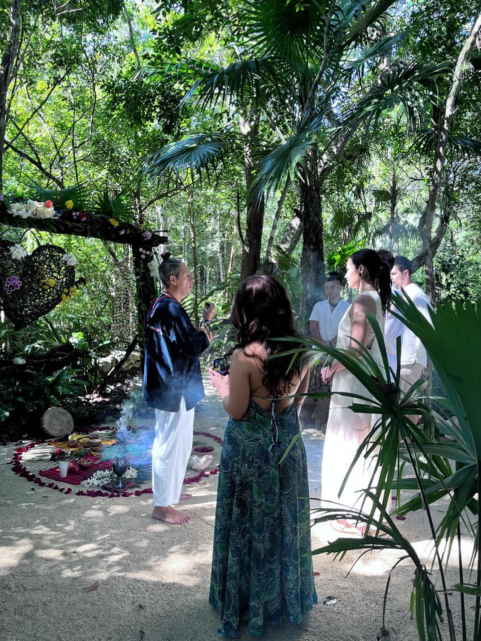 Guía espiritual realizando una ceremonia con incienso para personas vestidas de blanco en la selva.